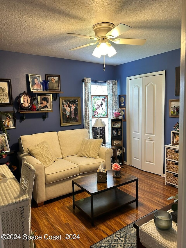 living room featuring a textured ceiling, ceiling fan, and dark wood-type flooring