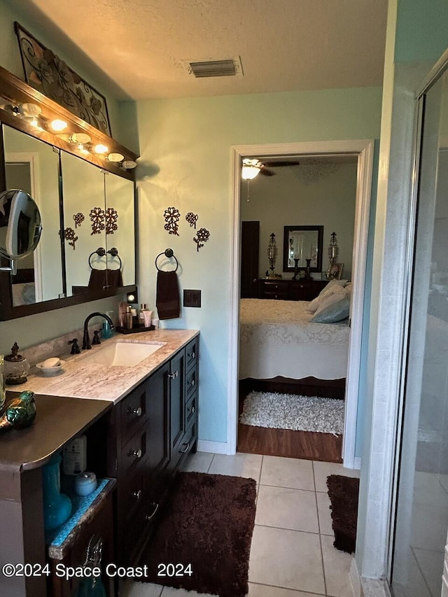 bathroom featuring vanity, a shower with door, tile patterned floors, ceiling fan, and a textured ceiling