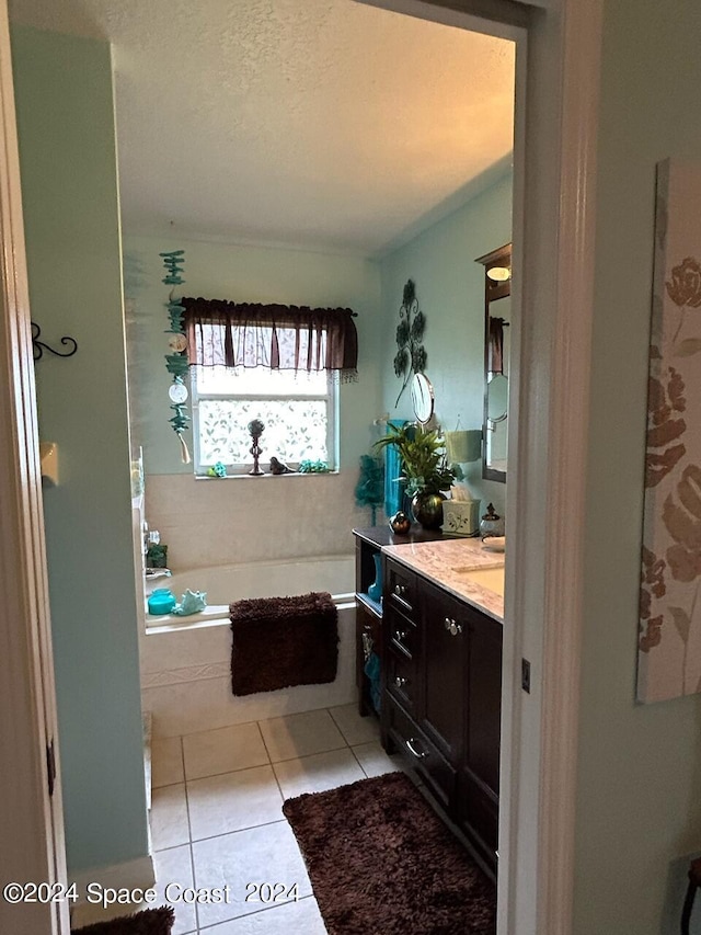 bathroom featuring tile patterned flooring, vanity, a tub, and a textured ceiling