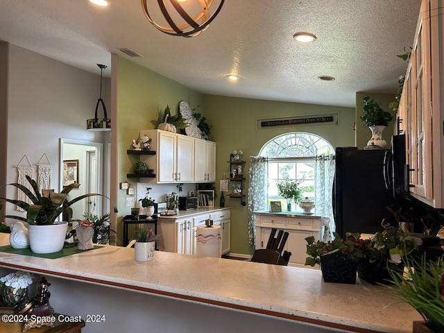 kitchen featuring kitchen peninsula, black refrigerator, a textured ceiling, hanging light fixtures, and lofted ceiling