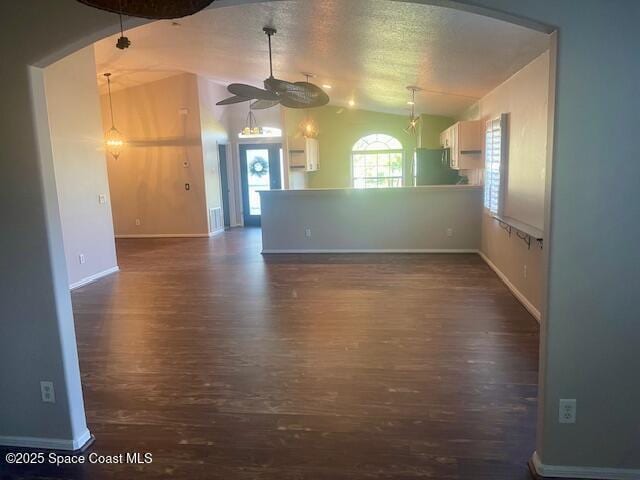 unfurnished room with ceiling fan, dark hardwood / wood-style flooring, lofted ceiling, and a textured ceiling