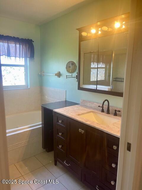 bathroom with tiled tub, tile patterned flooring, and vanity