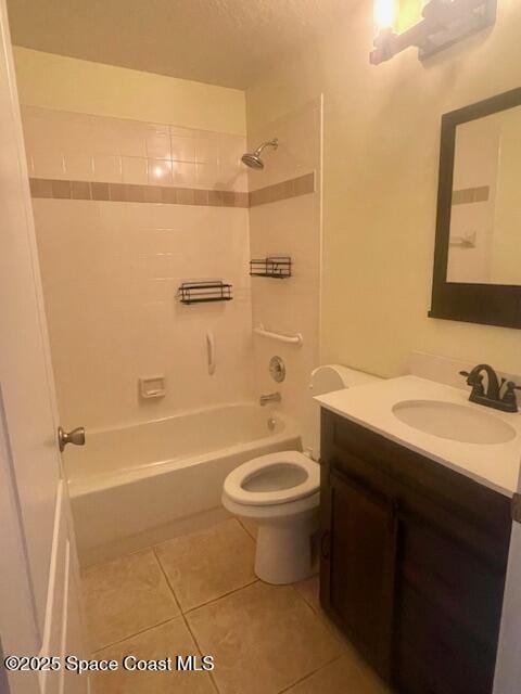 full bathroom featuring vanity, tiled shower / bath combo, a textured ceiling, tile patterned flooring, and toilet