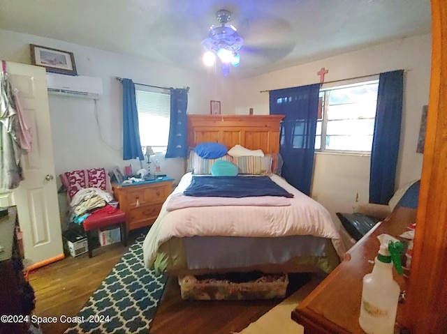 bedroom with a wall mounted air conditioner, dark hardwood / wood-style floors, and ceiling fan