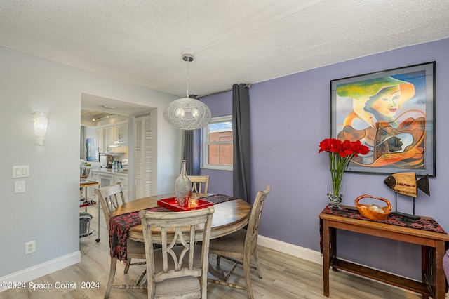 dining area featuring a textured ceiling and light hardwood / wood-style floors