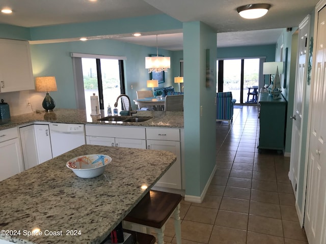 kitchen featuring white dishwasher, white cabinetry, light stone countertops, and sink