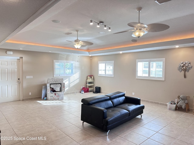 living area with a raised ceiling, visible vents, baseboards, and light tile patterned flooring