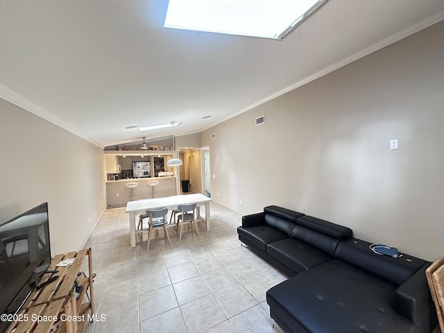 living area with lofted ceiling with skylight, visible vents, crown molding, and light tile patterned flooring