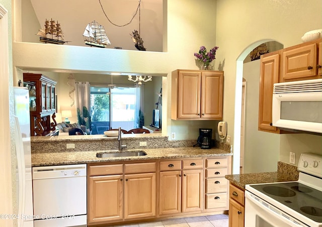 kitchen with white appliances, stone counters, light tile patterned flooring, and sink