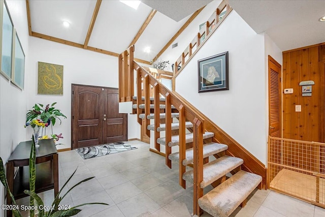 tiled foyer entrance with wooden walls and high vaulted ceiling