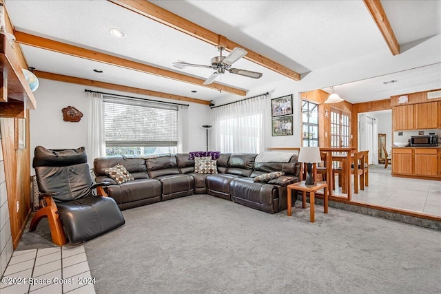 carpeted living room with a textured ceiling, beam ceiling, and ceiling fan