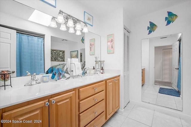 bathroom featuring tile patterned flooring, vanity, and a skylight