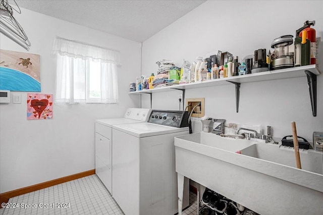 clothes washing area with a textured ceiling, light tile patterned flooring, separate washer and dryer, and sink