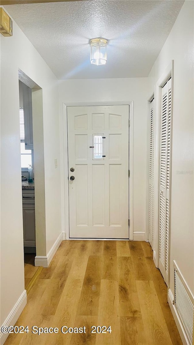 doorway featuring light hardwood / wood-style flooring and a textured ceiling