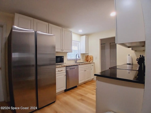 kitchen with sink, stainless steel appliances, light hardwood / wood-style floors, and white cabinetry