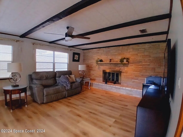 living room featuring a large fireplace, ceiling fan, beamed ceiling, and hardwood / wood-style flooring