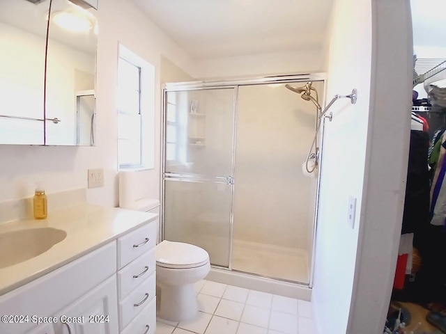 bathroom featuring tile patterned flooring, a shower with door, toilet, and vanity