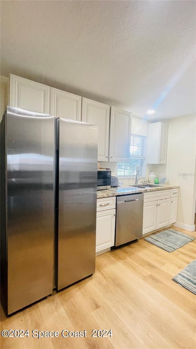 kitchen with light wood-type flooring, white cabinetry, sink, and stainless steel appliances