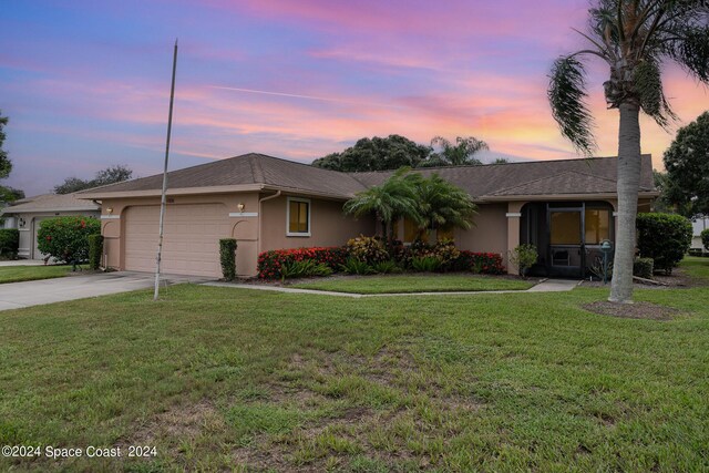 single story home featuring a garage and a lawn