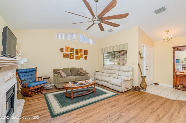 living room featuring vaulted ceiling, ceiling fan with notable chandelier, and light wood-type flooring