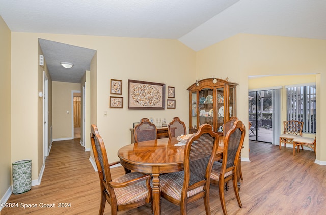 dining area with vaulted ceiling and light hardwood / wood-style flooring