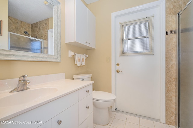 bathroom with tile patterned flooring, vanity, toilet, and walk in shower