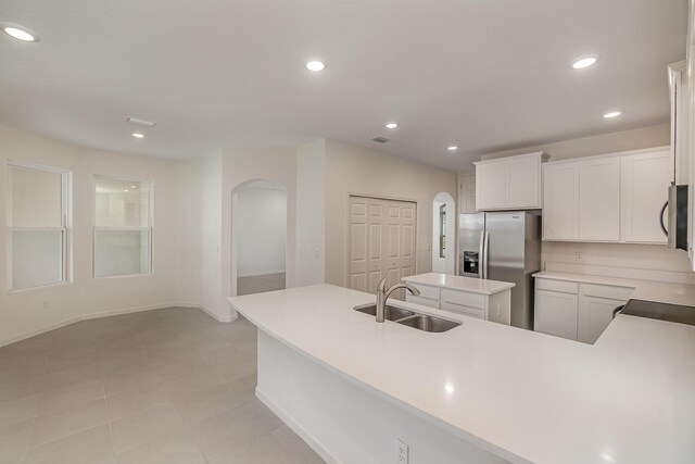 kitchen featuring stainless steel refrigerator with ice dispenser, a center island, white cabinetry, and sink