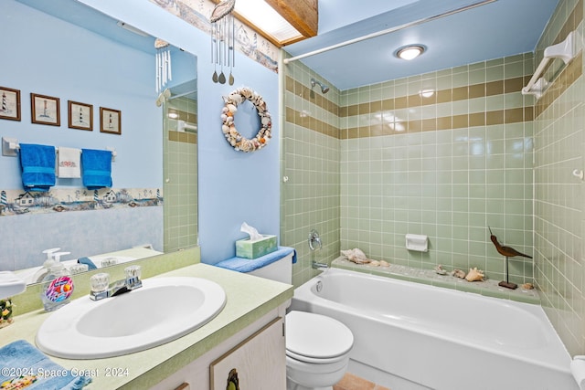 full bathroom featuring tiled shower / bath combo, vanity, and toilet