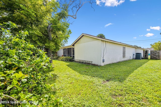 view of property exterior with a sunroom, cooling unit, and a yard