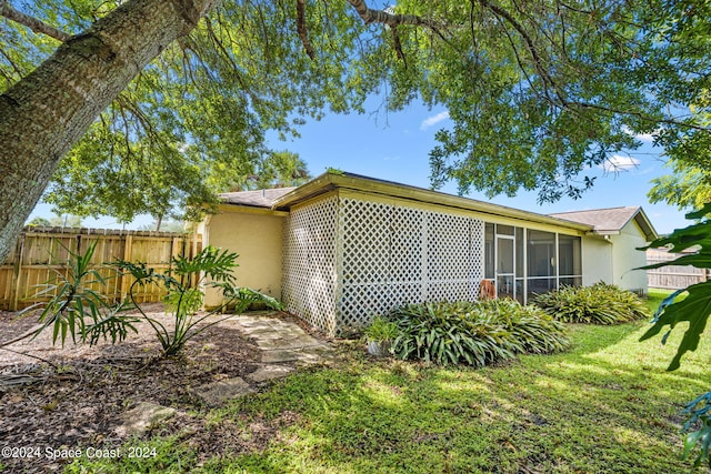 view of side of property featuring a sunroom and a yard