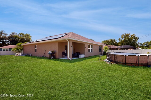 rear view of house featuring a lawn, solar panels, and a patio area