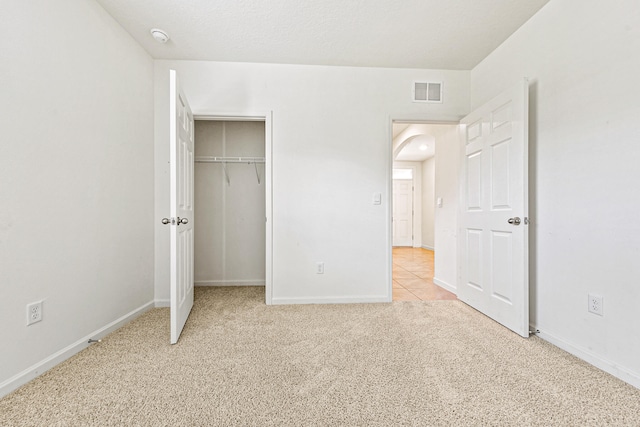 unfurnished bedroom with light colored carpet and a closet