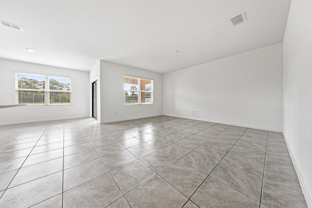 spare room with light tile patterned flooring and a textured ceiling