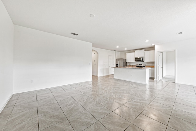 unfurnished living room featuring a textured ceiling and light tile patterned flooring