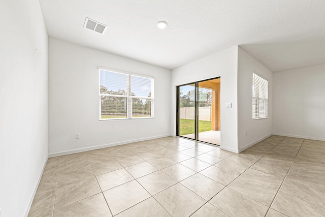 empty room featuring a textured ceiling and light tile patterned floors