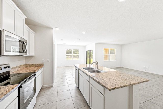 kitchen featuring a textured ceiling, sink, appliances with stainless steel finishes, a center island with sink, and white cabinets