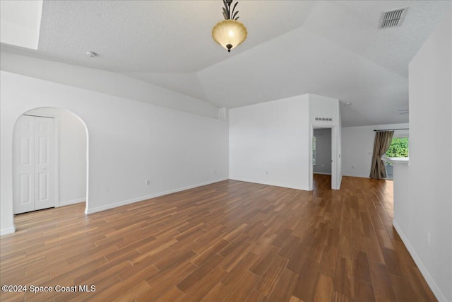 unfurnished living room featuring a textured ceiling, hardwood / wood-style flooring, and lofted ceiling