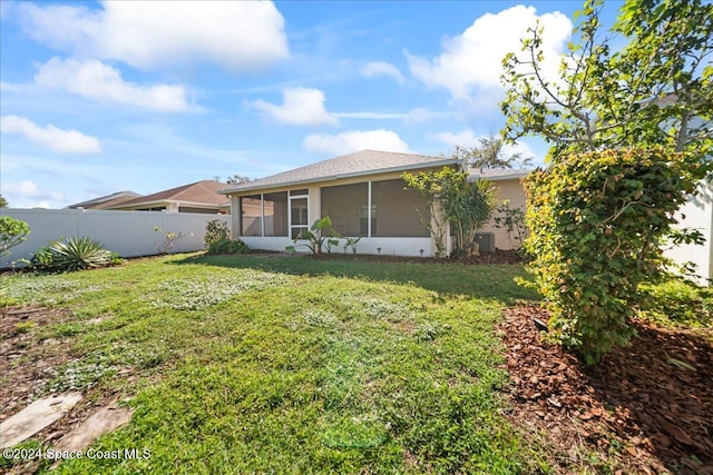 rear view of house with central AC unit, a lawn, and a sunroom