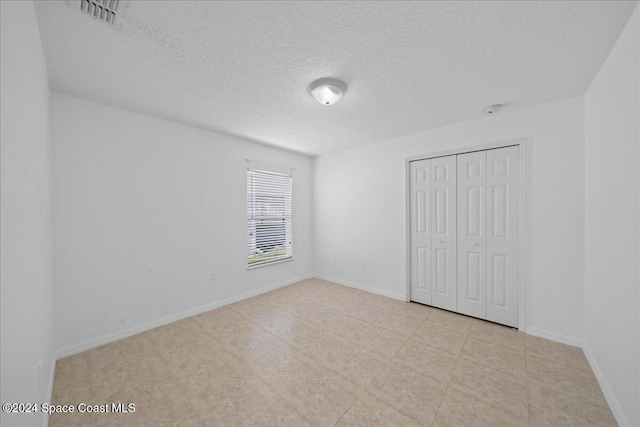 unfurnished bedroom with a textured ceiling and a closet