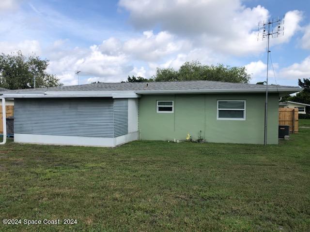 view of side of property with a lawn and cooling unit