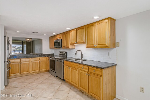 kitchen featuring light tile patterned flooring, sink, backsplash, stainless steel appliances, and dark stone counters