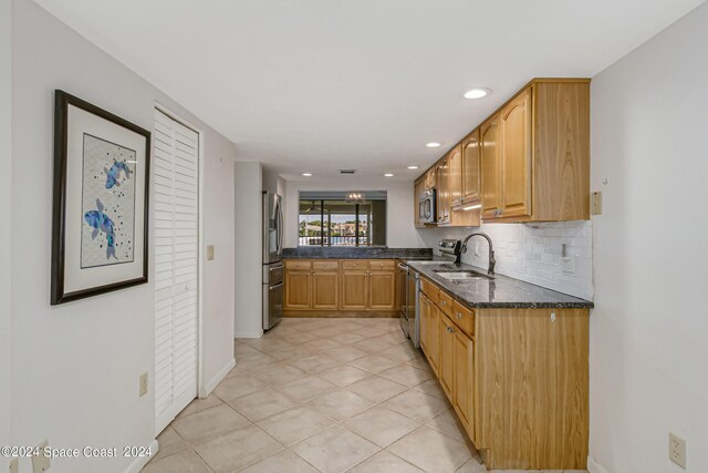 kitchen with dark stone counters, light tile patterned flooring, sink, backsplash, and appliances with stainless steel finishes