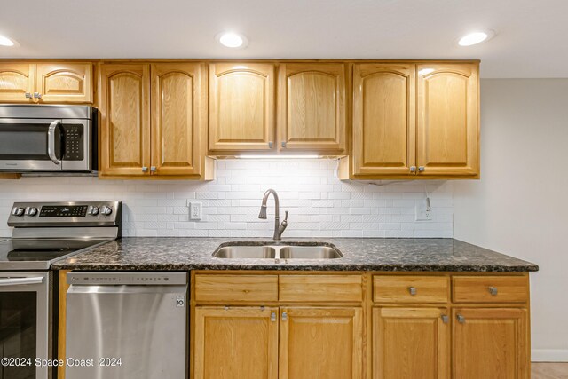 kitchen featuring dark stone counters, sink, stainless steel appliances, and tasteful backsplash