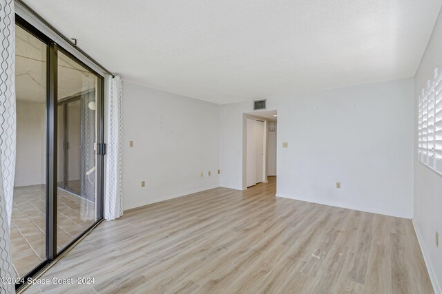 spare room with a textured ceiling and light hardwood / wood-style floors