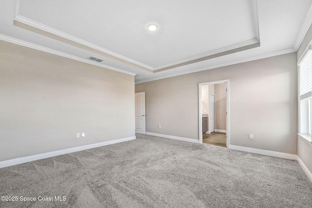 carpeted spare room with a raised ceiling and ornamental molding