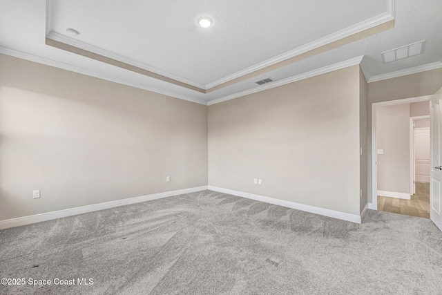 unfurnished room with a tray ceiling, crown molding, and light colored carpet