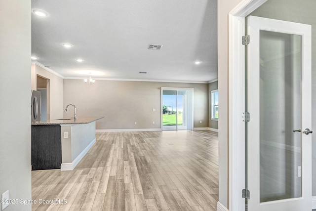 interior space featuring a notable chandelier, light hardwood / wood-style floors, sink, and crown molding