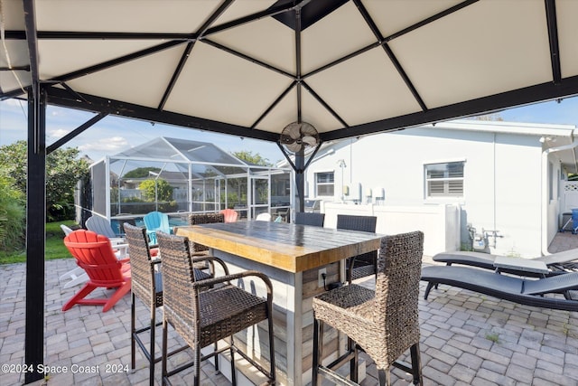 view of patio with an outdoor bar and glass enclosure