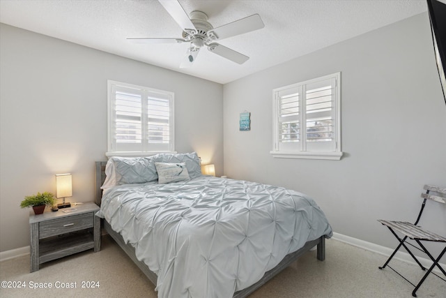 bedroom with ceiling fan, light colored carpet, and a textured ceiling