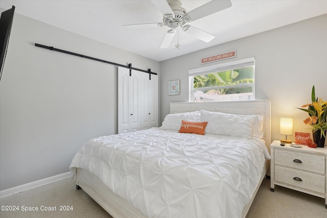 carpeted bedroom featuring ceiling fan, a textured ceiling, a closet, and a barn door